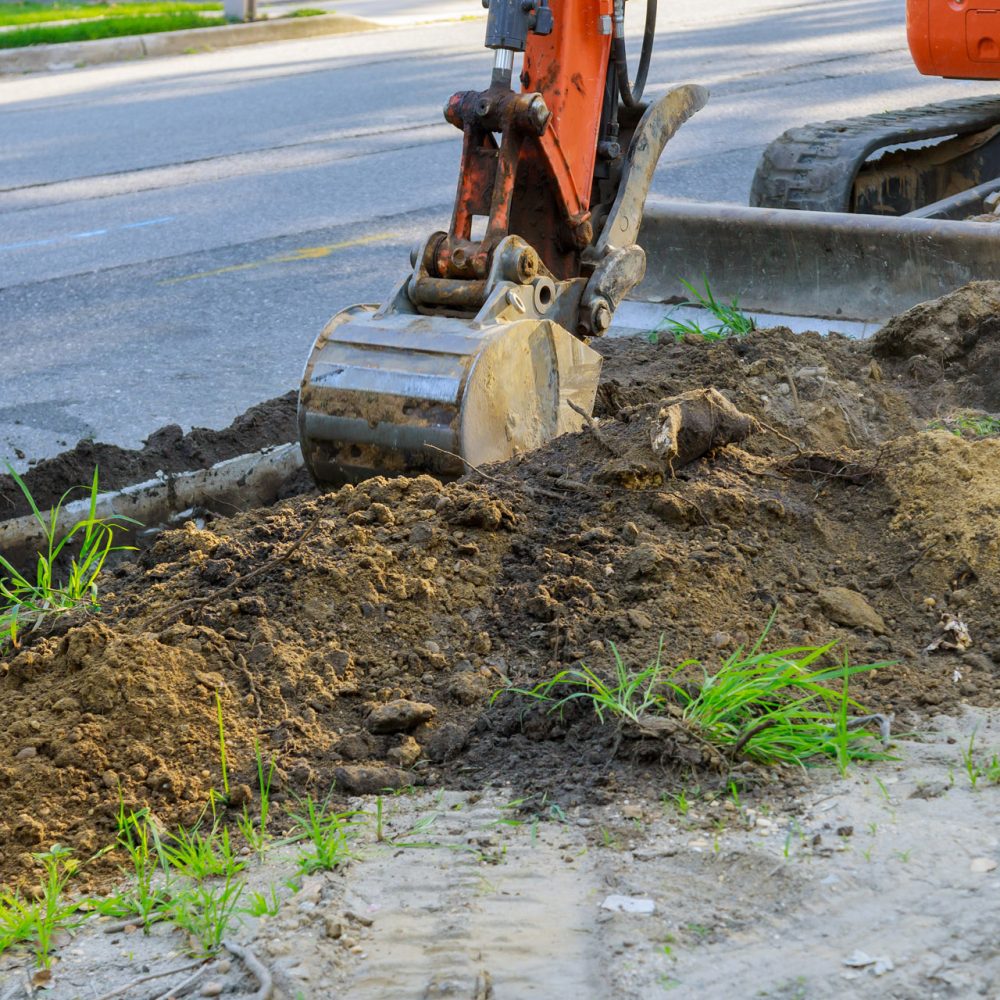 Digger working at construction in excavation pit Backhoe on road work digger working at construction in excavation pit